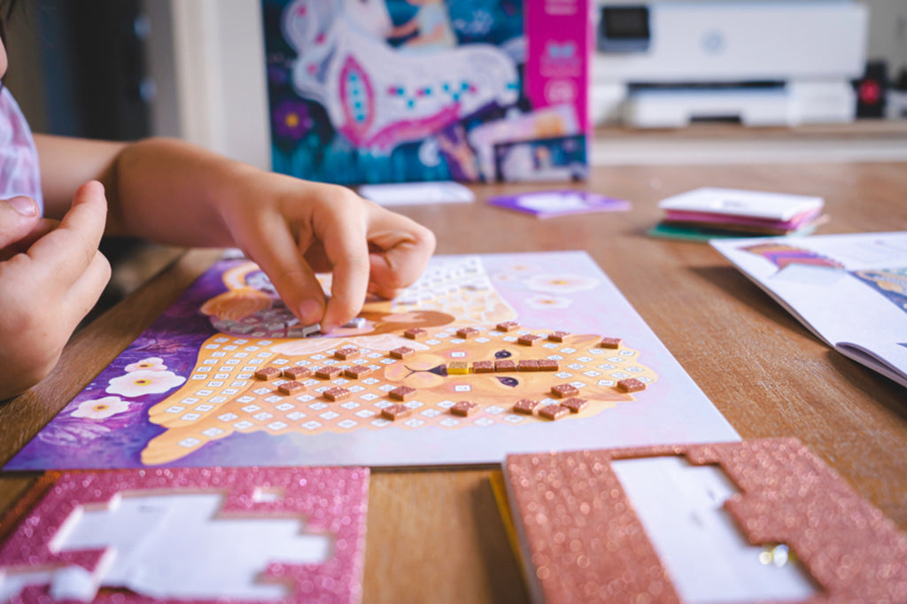 Full contents of the Djeco Enchanted World mosaic kit laid out: boards, foam sheets, rhinestones and booklet