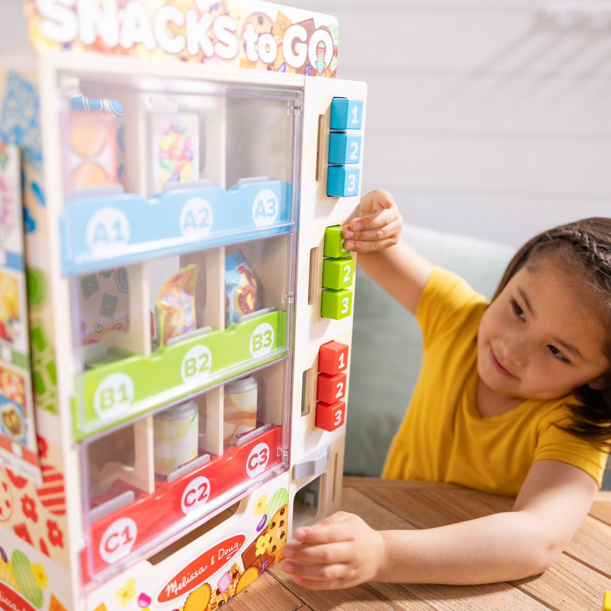 Close-up of the numbered selection buttons and snack compartments on the Melissa & Doug vending machine