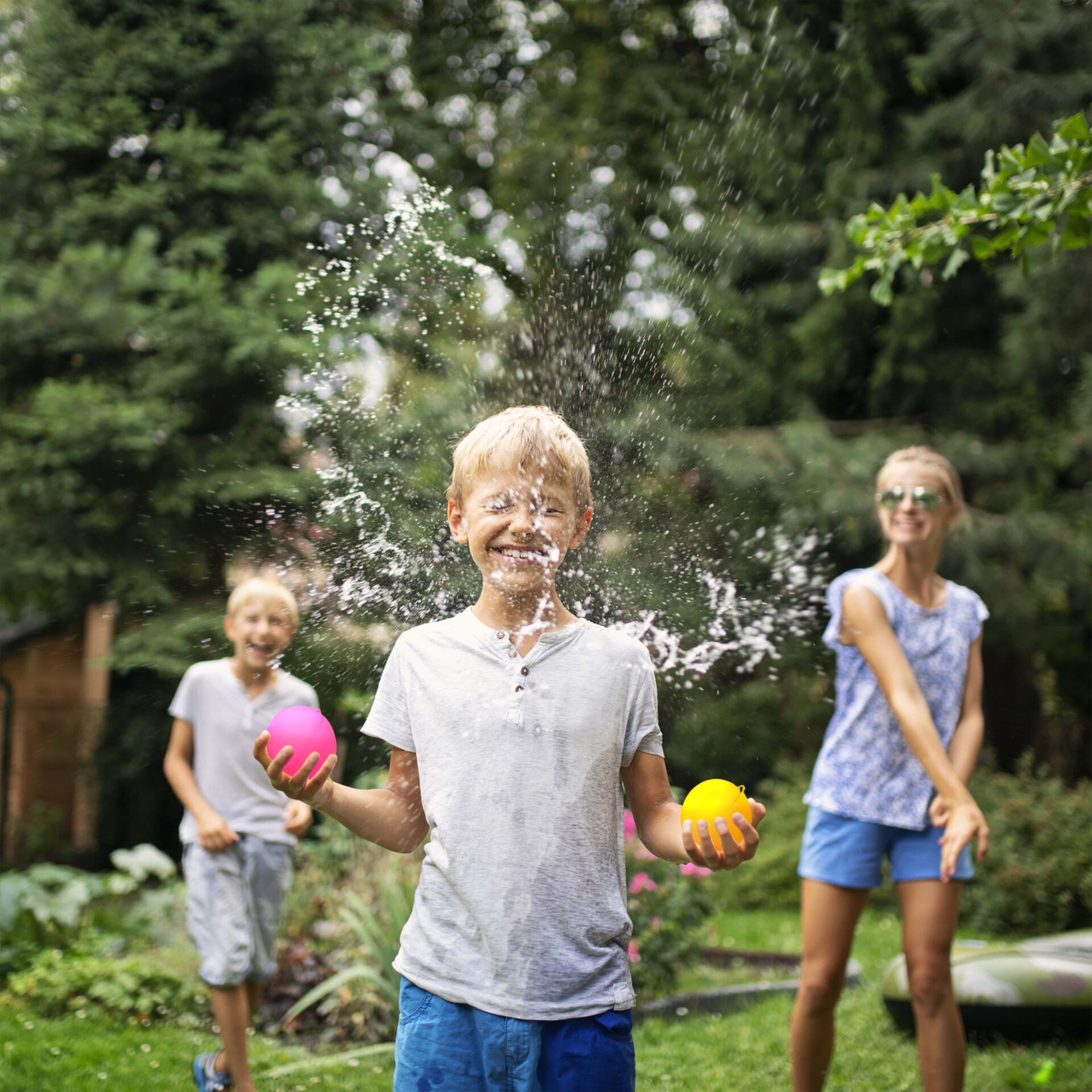 Children playing with water balloons in a garden