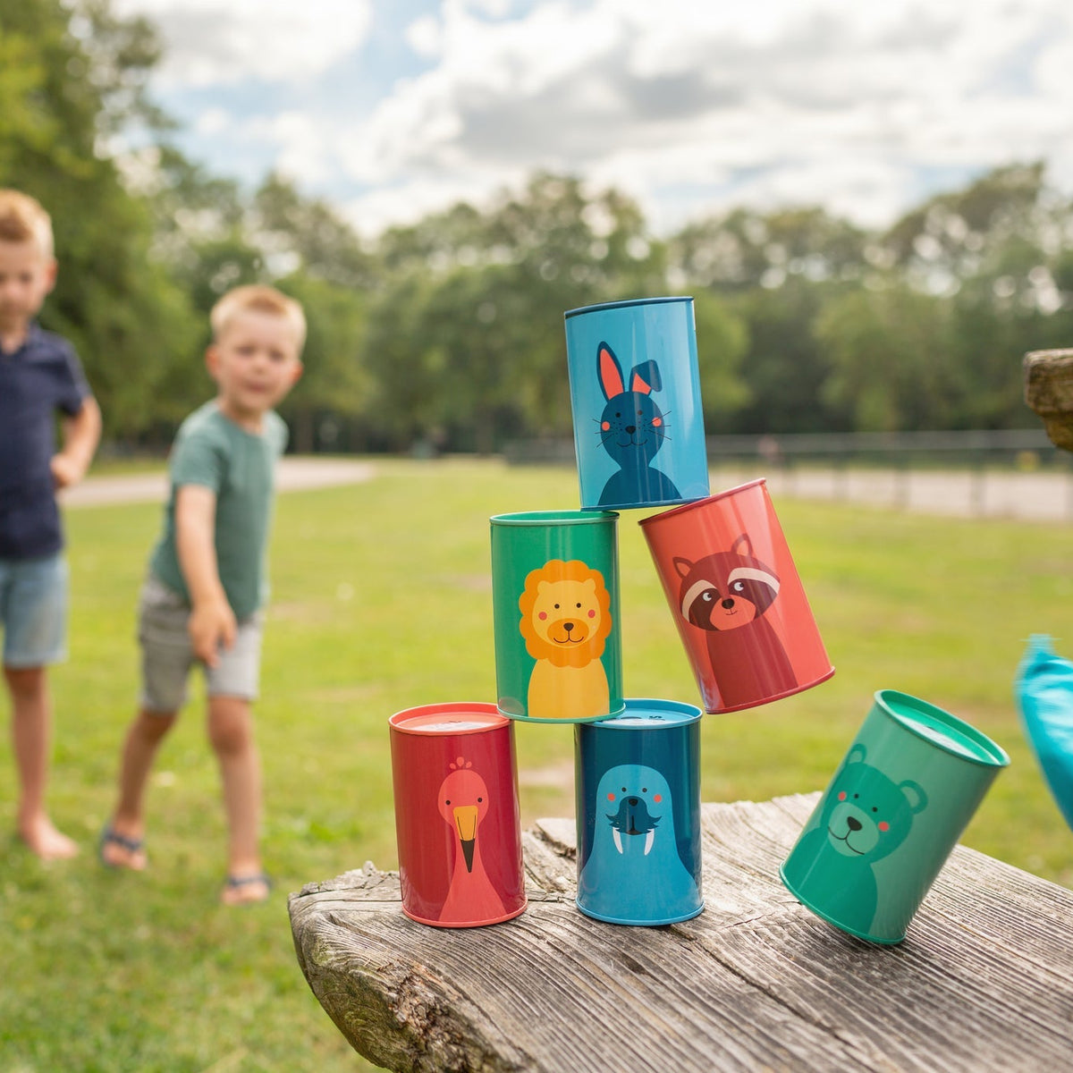 Children playing with colorful cups stacked on a wooden log outdoors