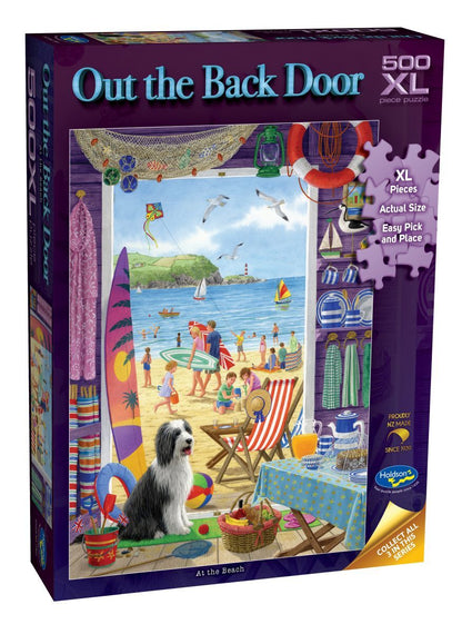 A 500-piece jigsaw puzzle box titled 'Out the Back Door' by Castle Builders. The box features a colorful illustration of a beach scene viewed from inside a house, with a black and white dog in the foreground.