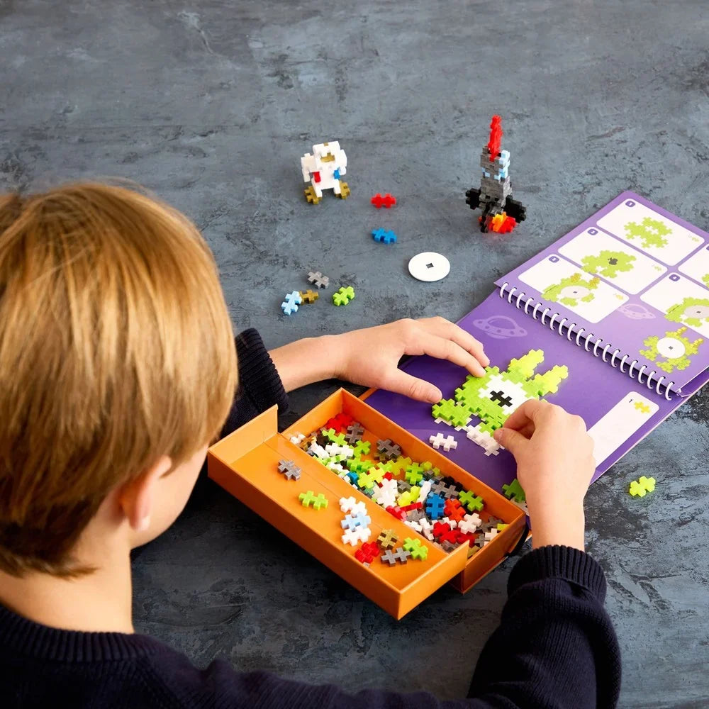 The activity pad opened flat showing a numbered space page and the attached storage box