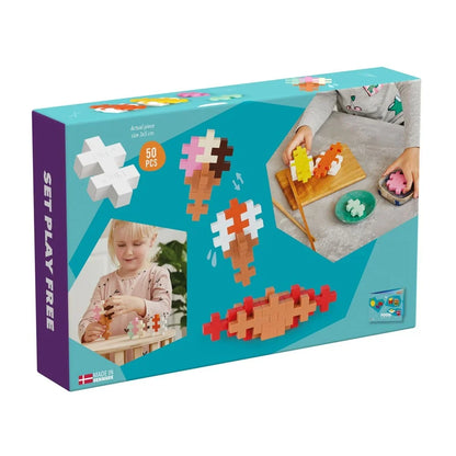 Fifty chunky Plus-Plus BIG pieces laid out beside the illustrated food idea booklet