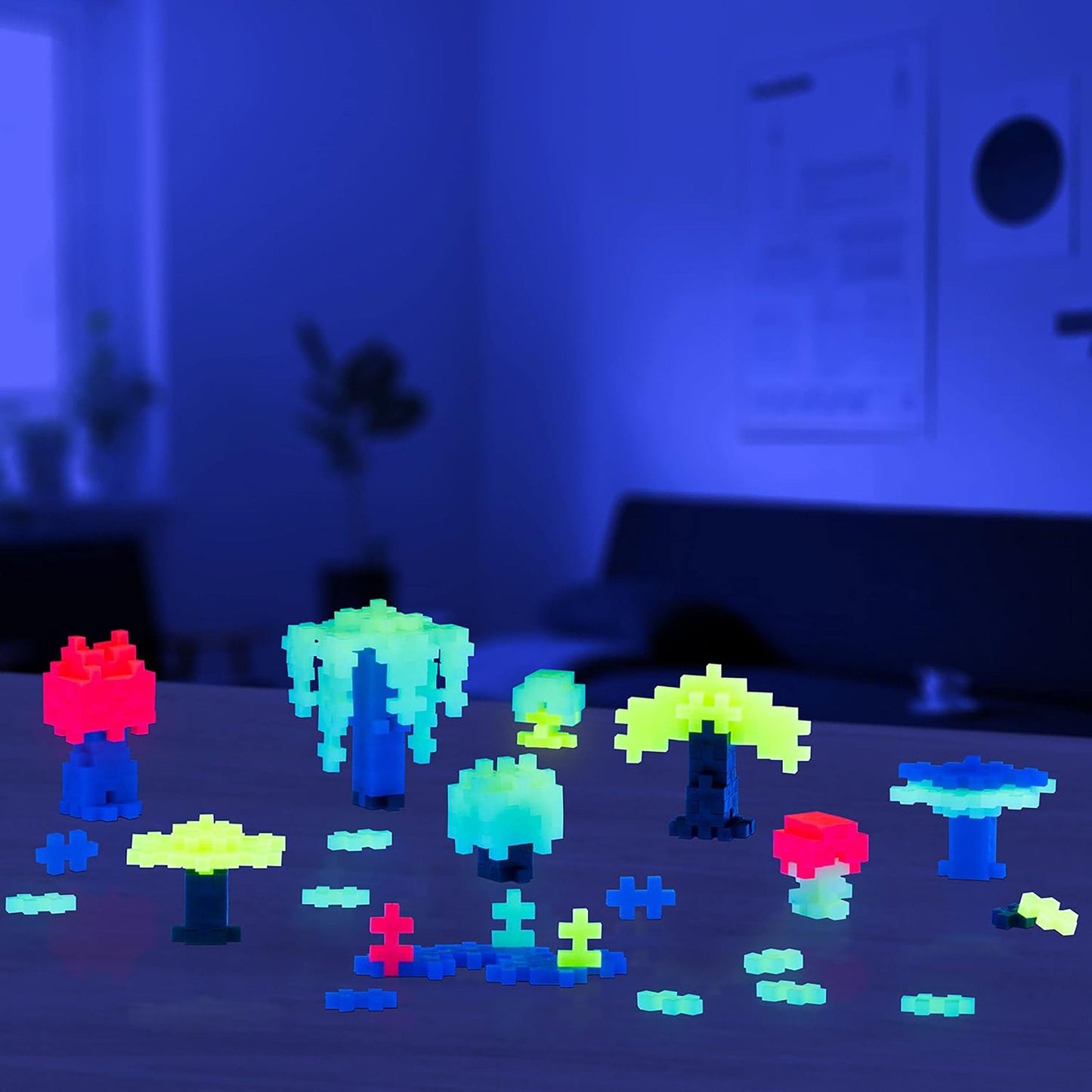Loose Plus-Plus pieces in coral, black, neon blue, neon yellow and glow shades in daylight