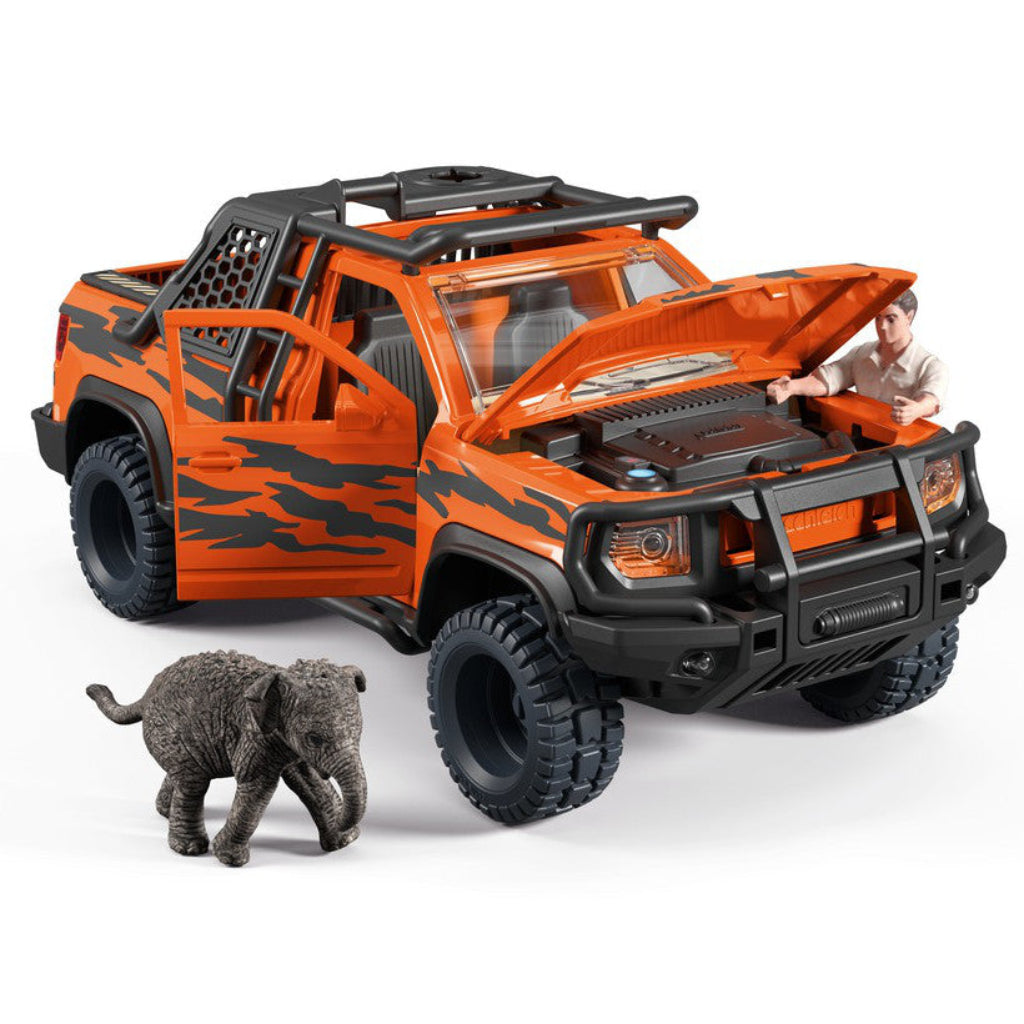 Schleich orange and black toy pickup truck with a small gray elephant figurine in front, A ranger figure is visible looking inside the open hood