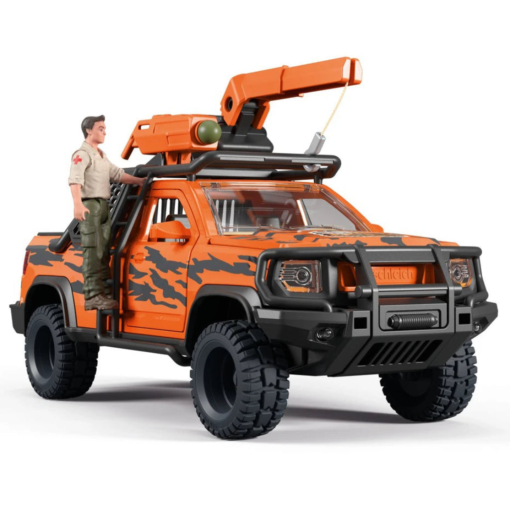 Orange and black toy pickup truck with a mounted crane on top, shown on a white studio background. A small toy soldier figure stands on the front door of the truck.