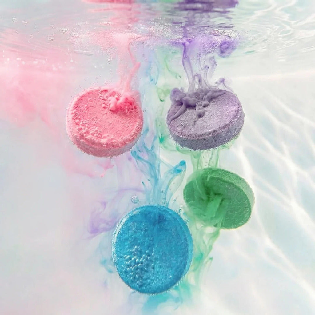Bath fizzer dissolving in the tub, releasing fizzing bubbles and colouring the bath water