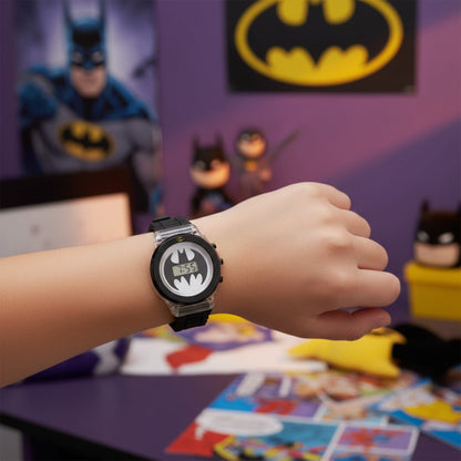 Child wearing a DC Batman flashing LCD watch with black strap and Batman logo digital display, surrounded by Batman-themed toys and decorations.