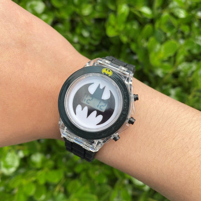 DC Batman black flashing LCD children's watch worn on a wrist outdoors, showing the Batman logo digital display and transparent watch case.