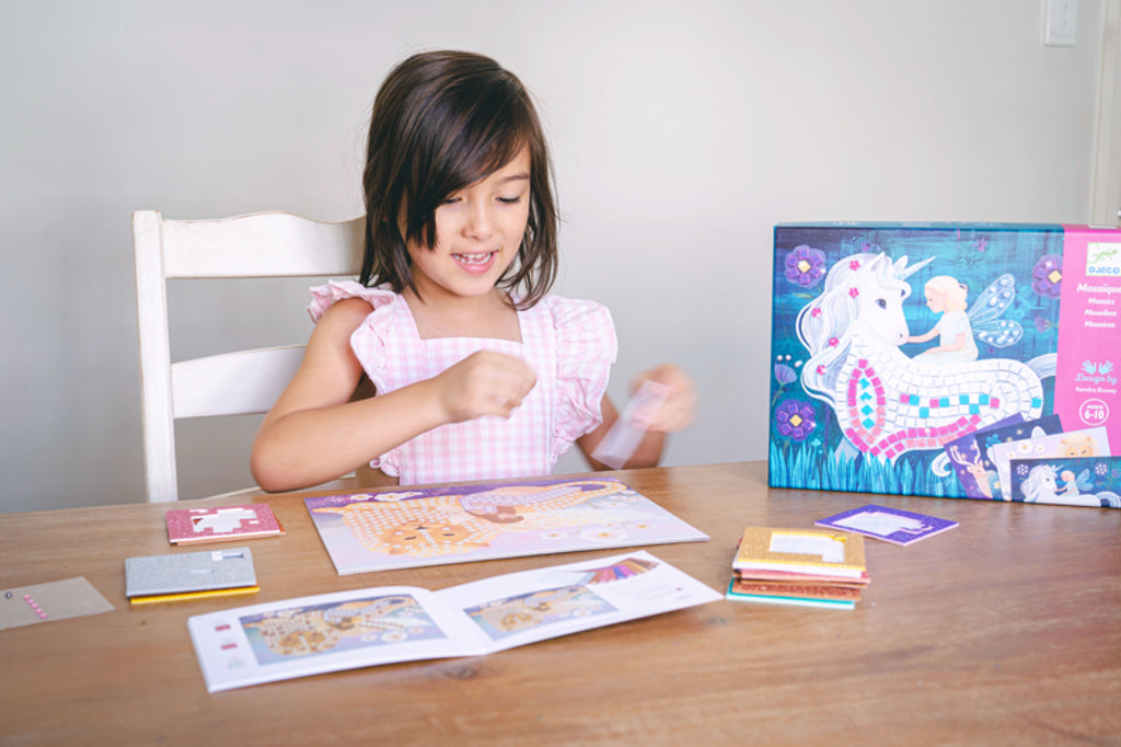 Child pressing glitter foam squares onto a Djeco Enchanted World board during a calm crafting session