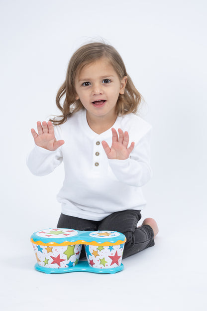 Toddler tapping out a rhythm with open hands on Halilit Baby Bongos during music time at home
