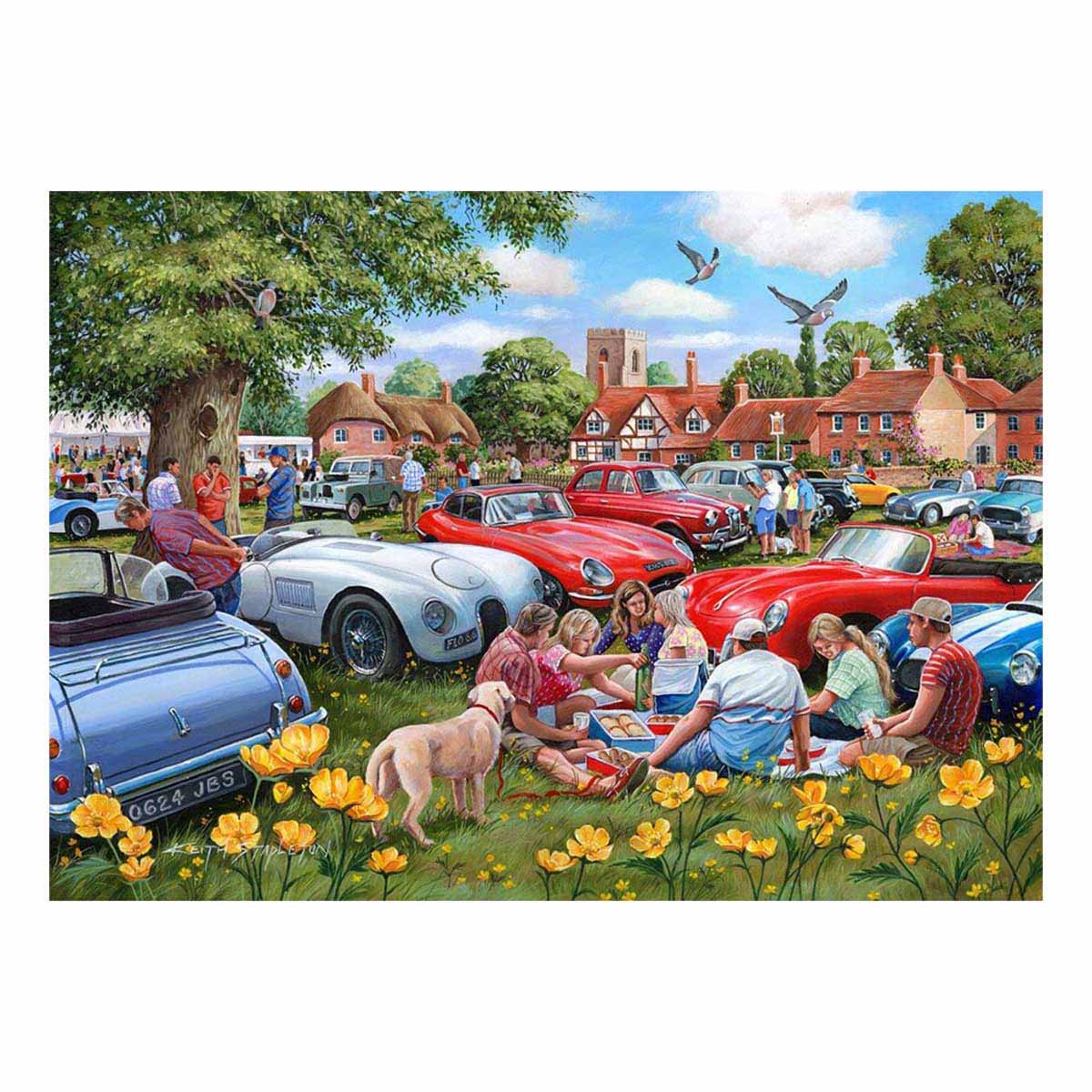 People enjoying a picnic by vintage cars in a village setting with flowers and trees.