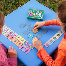 Two children playing eeBoo Little Beetles Memory & Matching Game outdoors, turning over colourful beetle cards to find matching pairs.