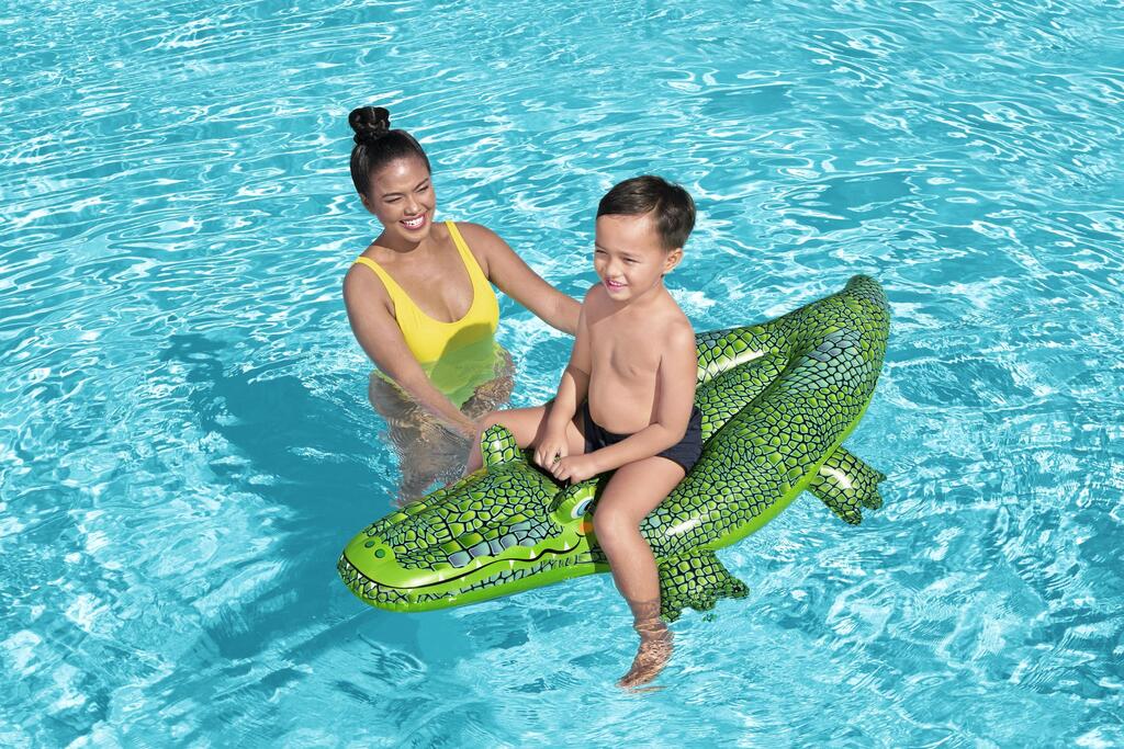 Child sitting astride the Bestway inflatable crocodile pool float holding the moulded grab handles