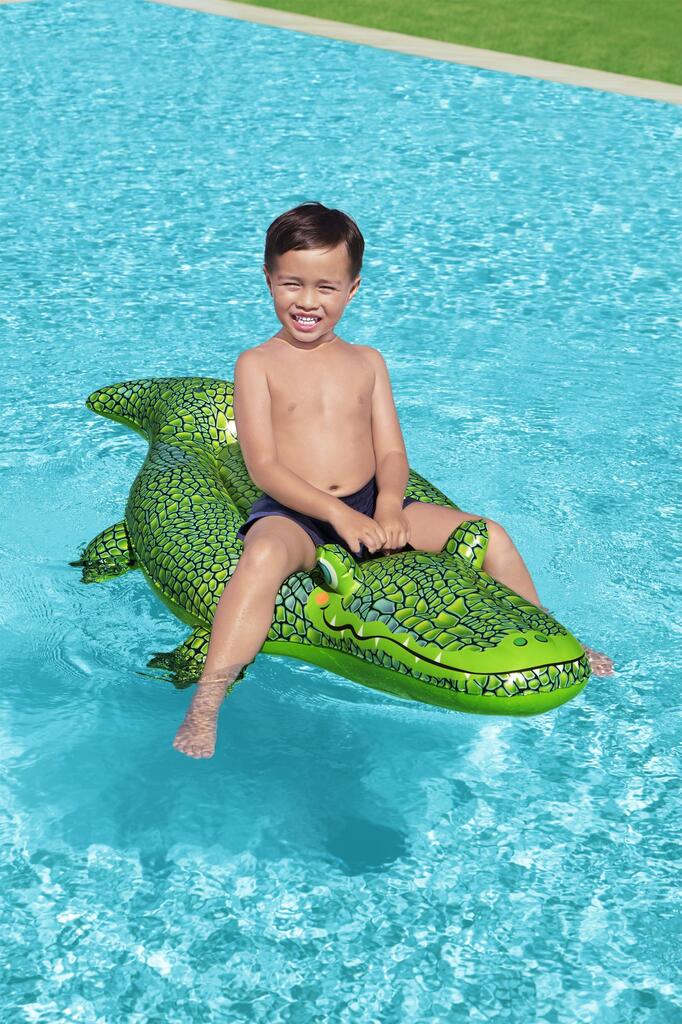 Child riding the Bestway inflatable crocodile pool float in a backyard swimming pool in summer