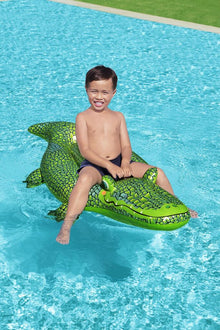 Child riding the Bestway inflatable crocodile pool float in a backyard swimming pool in summer