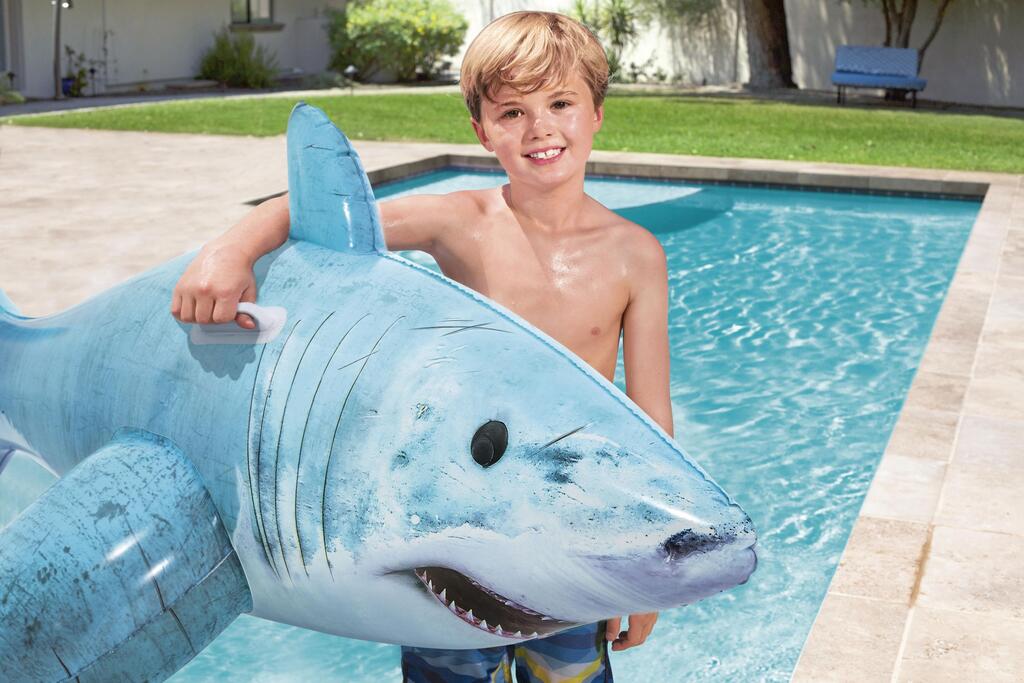 Child riding the Bestway inflatable shark pool float in a backyard swimming pool in summer