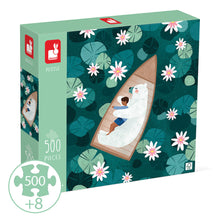 Janod Water Lilies 500-piece jigsaw puzzle box art showing a boy resting on a sleeping polar bear in a wooden boat, surrounded by lily pads and white flowers