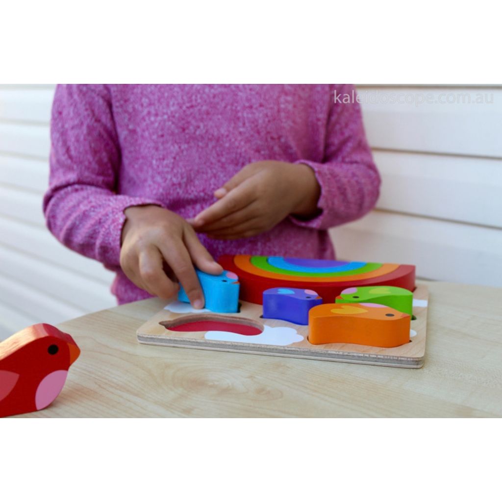 Toddler placing a rainbow piece into the Kiddie Connect bird and rainbow wooden puzzle board
