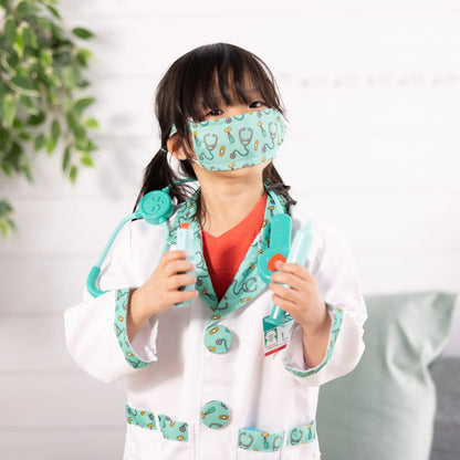 Young child dressed in the doctor costume and stethoscope, pretending to examine a teddy bear patient at home