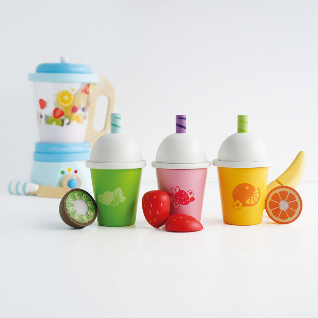 Child holding a Le Toy Van Honeybake wooden smoothie cup while serving customers in pretend cafe play