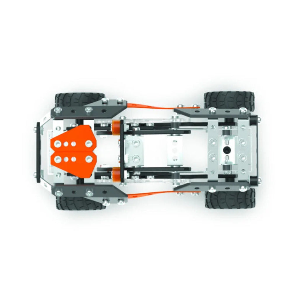 Top-down view of a toy vehicle chassis with four black wheels, a gray metal frame, and bright orange mechanical components, shown on a plain white background.