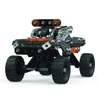 A toy off-road vehicle built from interlocking blocks, featuring black tires, a black chassis, silver metal beams, and orange accents, shown on a white background.