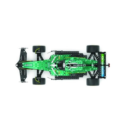 A top-down view of a green and black remote control toy race car chassis with four wheels, shown on a solid white background.
