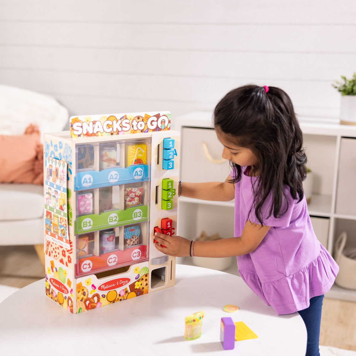Child using the coloured selection buttons on the Melissa & Doug wooden vending machine