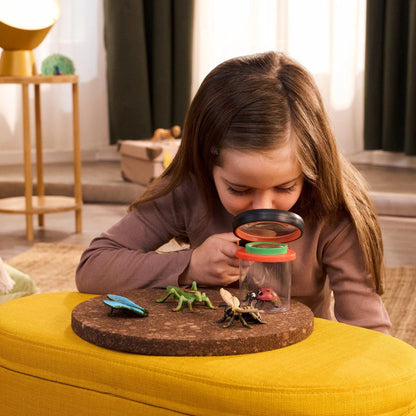 Child comparing a Schleich insect figure against a real bug found in the garden outdoors