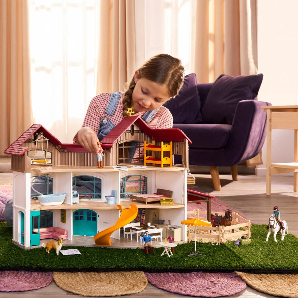Child playing with the Schleich Lakeside Villa horse playset and paddock on a living room floor