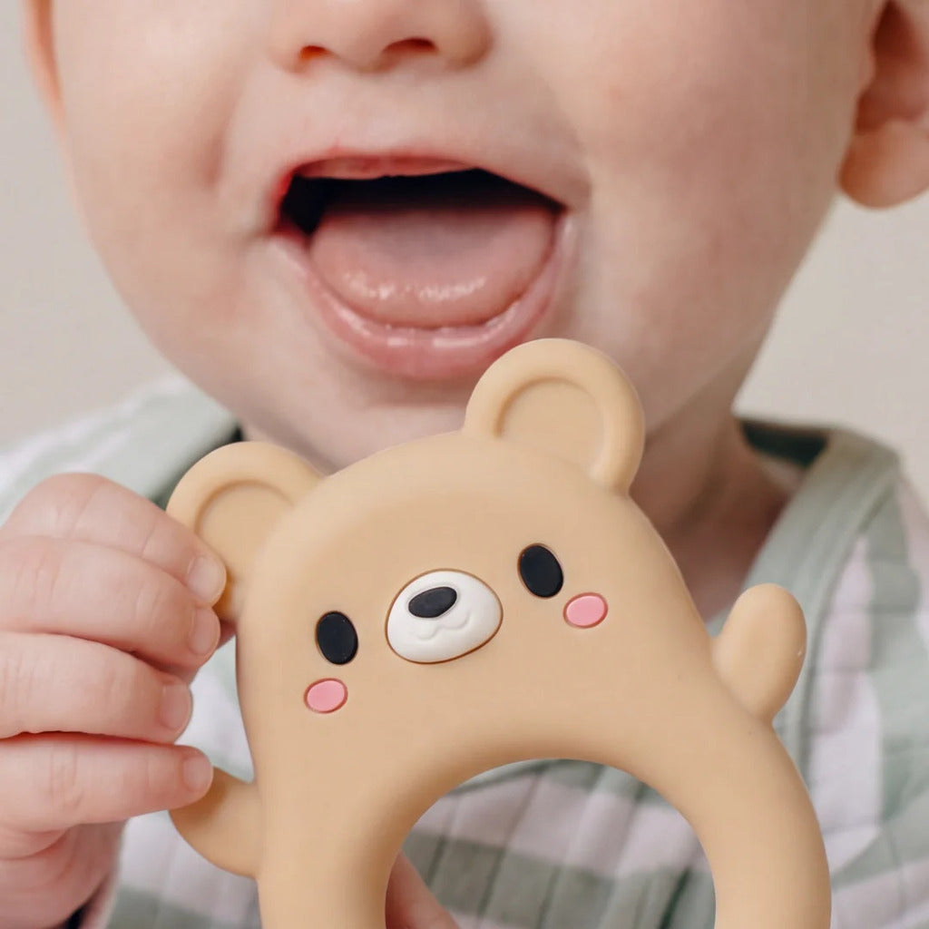 Bear silicone teether held between two fingers to show the ring size against an adult hand