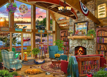 Cozy living room with large windows, fireplace, and bookshelves.