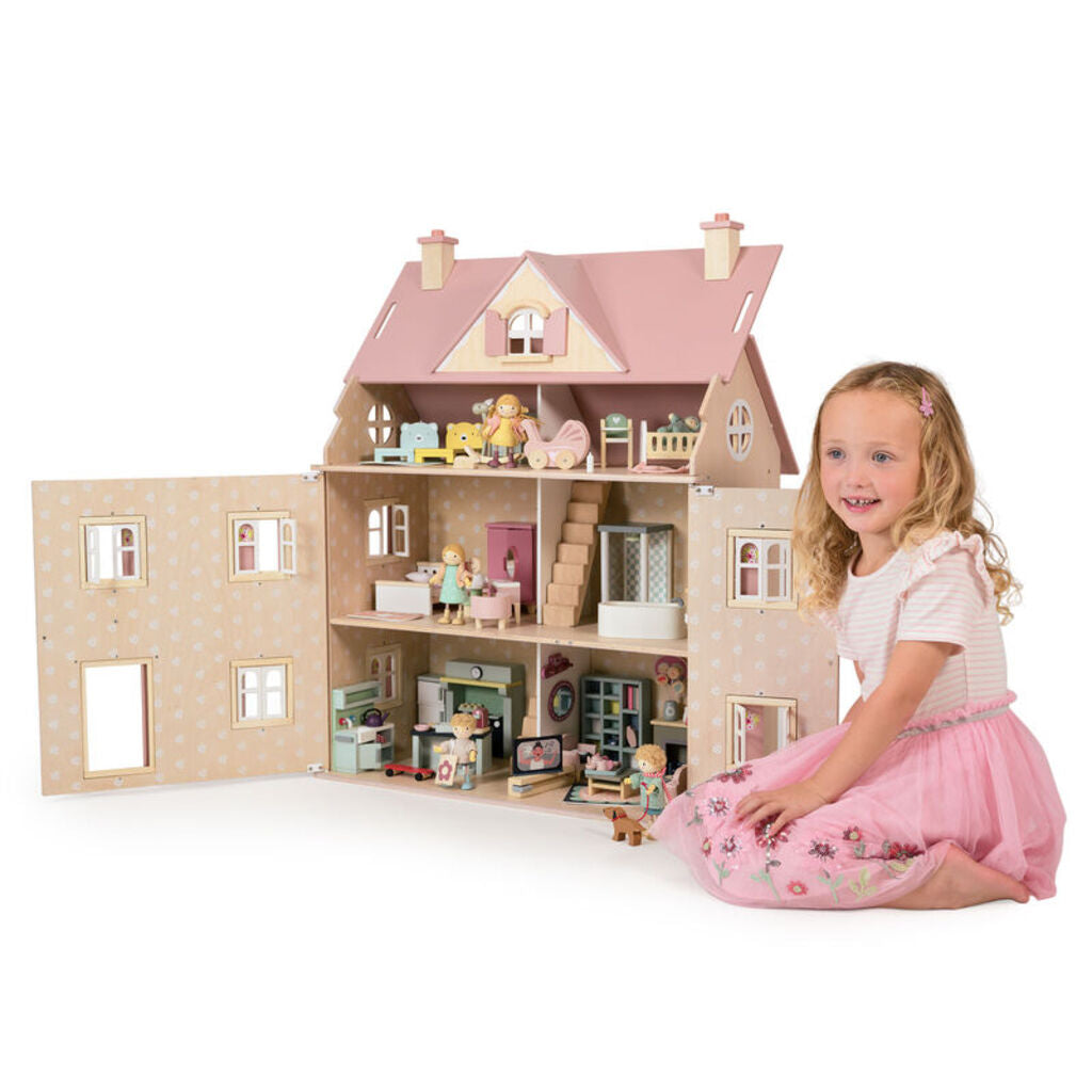 Child playing with dolls on the staircase between floors of the open wooden house