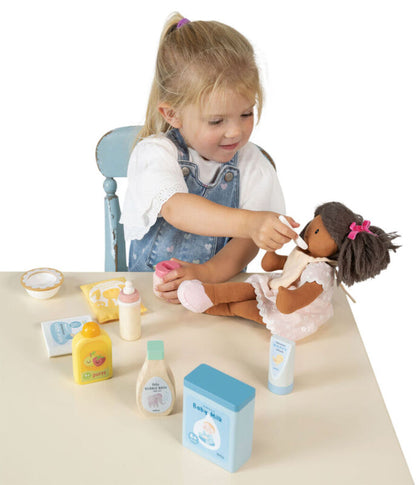 The feeding pieces together: wooden bottle, bowl, spoon and bib laid out side by side