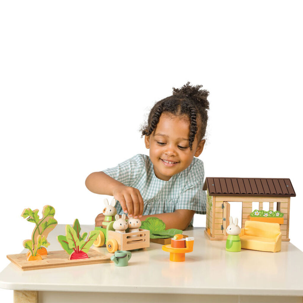 a child lifting a wooden carrot out of the vegetable patch inside the garden shed
