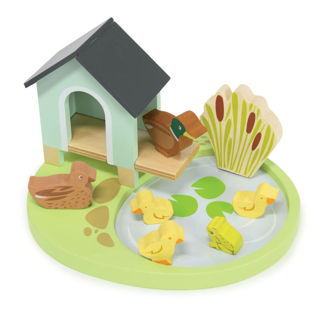 The wooden duck house and reeds shown from the side with the frog beside them