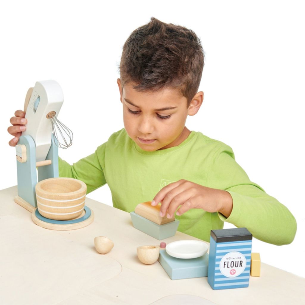 Child pretending to bake with the Tender Leaf Toys wooden Home Baking set in a play kitchen