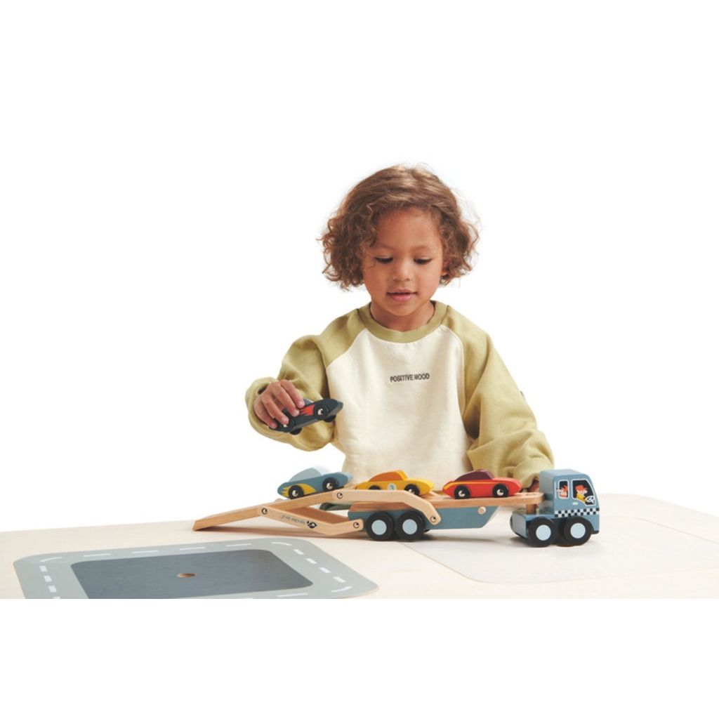 Small wooden cars loaded onto the Tender Leaf Toys car transporter truck trailer