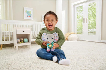 Cuddle & Sing Elephant held in an adult hand to show the plush toy's size for a young baby