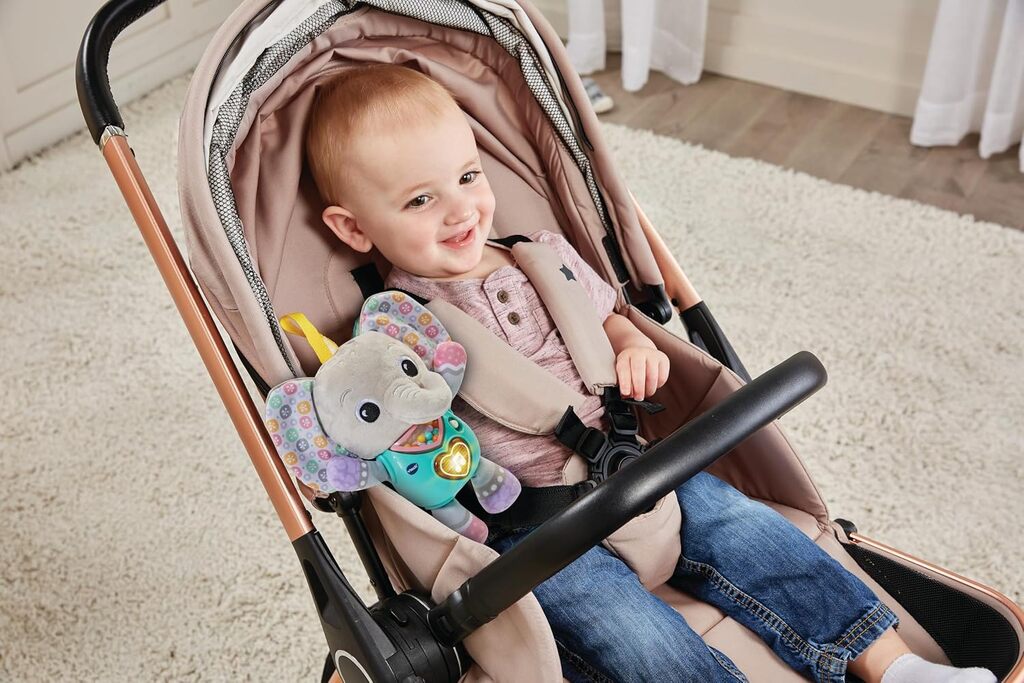 Baby lying on a play mat cuddling the VTech Cuddle & Sing Elephant soft plush toy during floor time