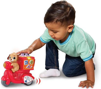 Toddler pushing the Dash 'n' Deliver Scooter across a kitchen floor during pretend delivery play
