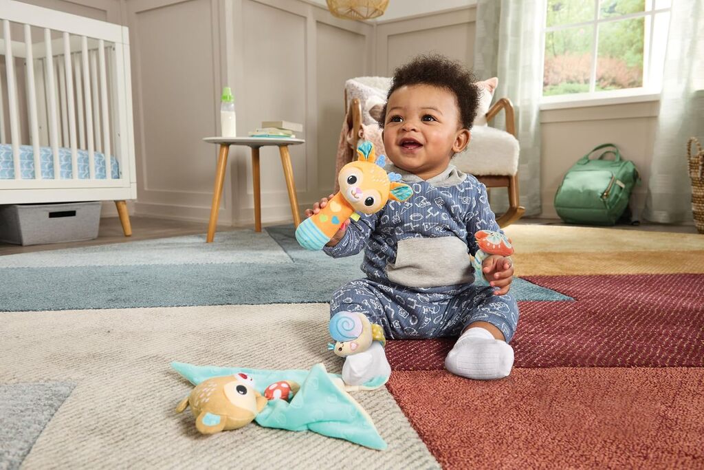 Parent holding a Forest Pals character above a baby during tummy time on a soft play mat