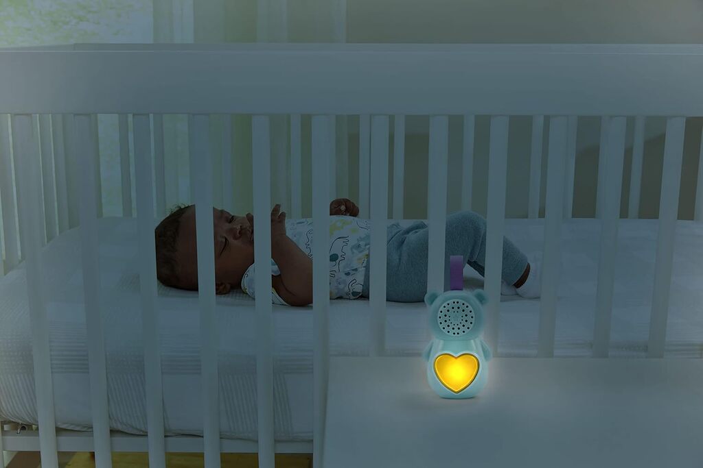 Baby Soothing Bear glowing softly beside a sleeping baby's cot in a darkened nursery