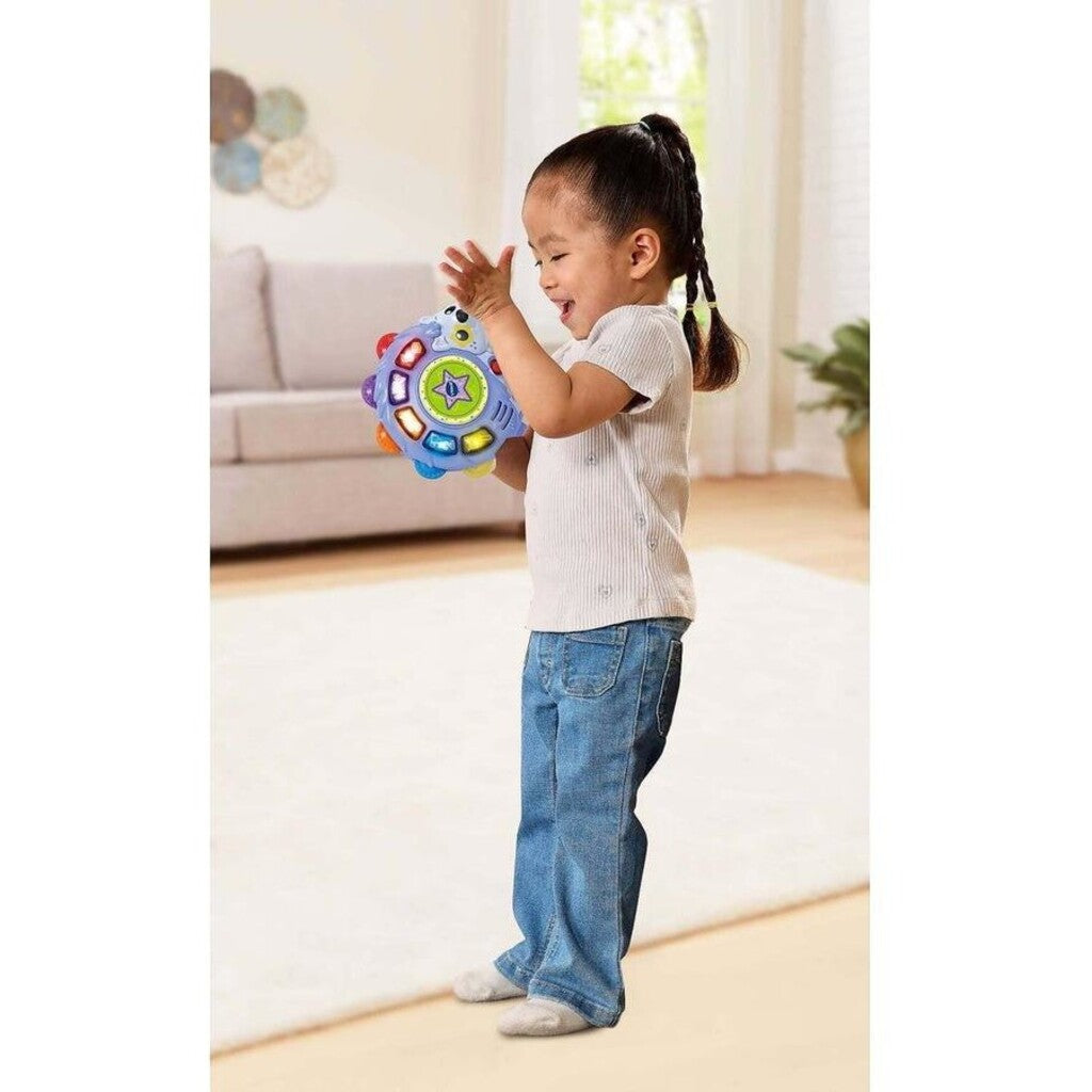 Toddler shaking the Tapping Tunes Tambourine while dancing in a bright living room