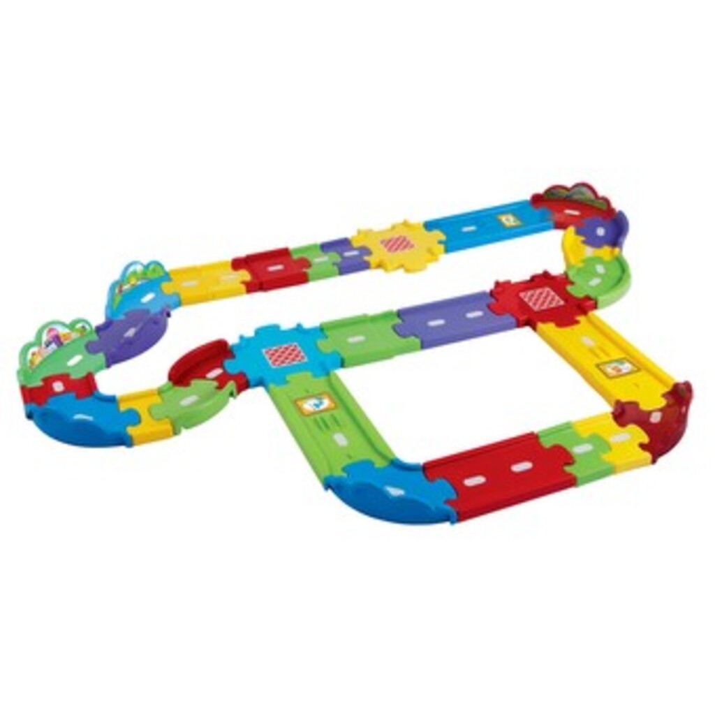 Toddler pushing a Toot-Toot Drivers vehicle around the assembled 30-piece track on a living room rug