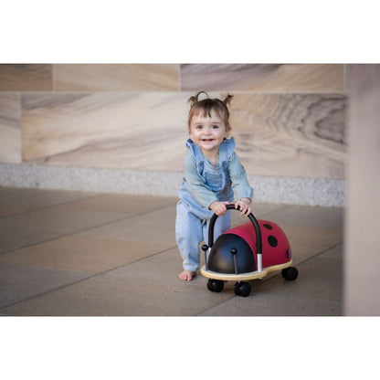 Toddler riding the Wheely Bug small ladybug across a smooth floor, building balance and coordination
